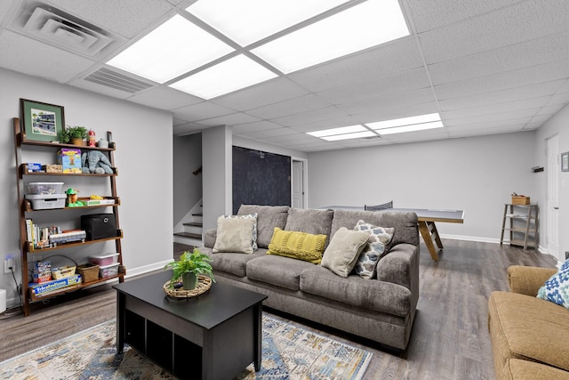 living room featuring dark hardwood / wood-style flooring and a drop ceiling