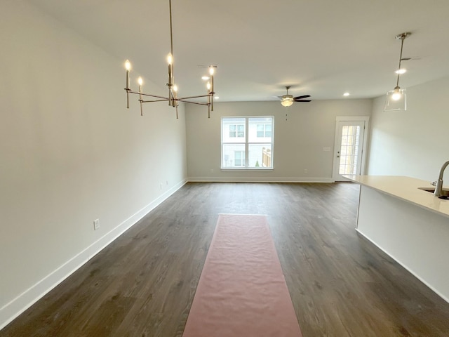 unfurnished dining area featuring ceiling fan with notable chandelier, dark hardwood / wood-style flooring, and sink