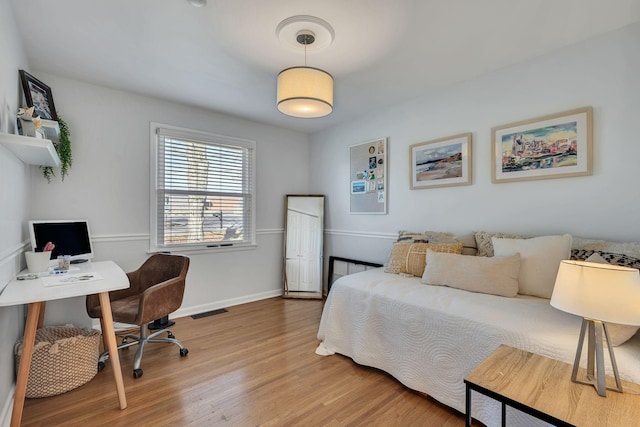 bedroom with wood finished floors, visible vents, and baseboards