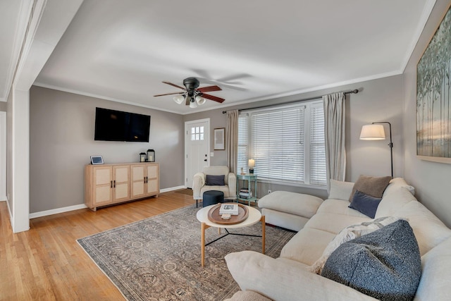 living room with a ceiling fan, baseboards, crown molding, and light wood finished floors