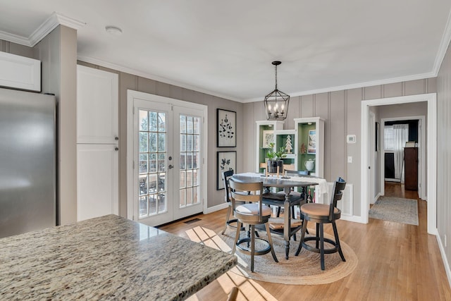 dining area featuring french doors, crown molding, and light wood finished floors