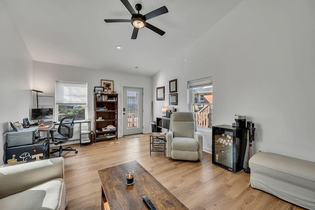 living area featuring lofted ceiling, ceiling fan, plenty of natural light, and light wood-style flooring