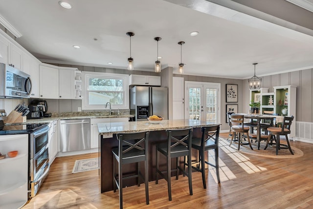 kitchen with hanging light fixtures, appliances with stainless steel finishes, a kitchen island, and white cabinetry