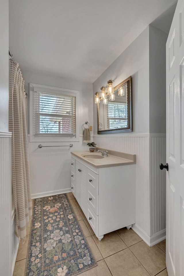 full bathroom featuring tile patterned flooring, vanity, and wainscoting