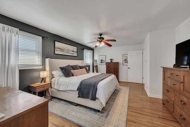 bedroom featuring ceiling fan, light wood finished floors, and baseboards