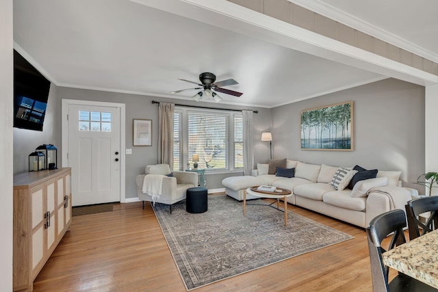 living room with baseboards, light wood finished floors, a ceiling fan, and crown molding