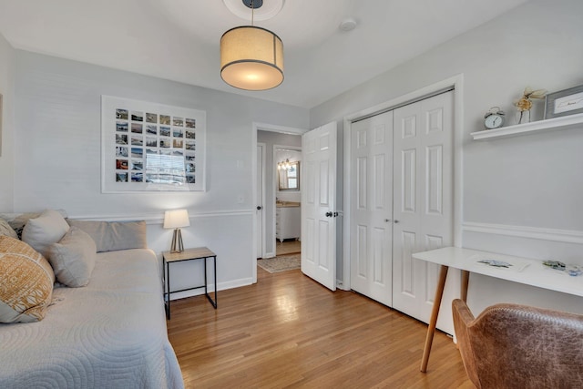 bedroom with light wood-style floors, baseboards, and a closet