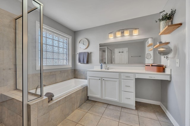 full bathroom featuring a garden tub, a shower stall, vanity, baseboards, and tile patterned floors