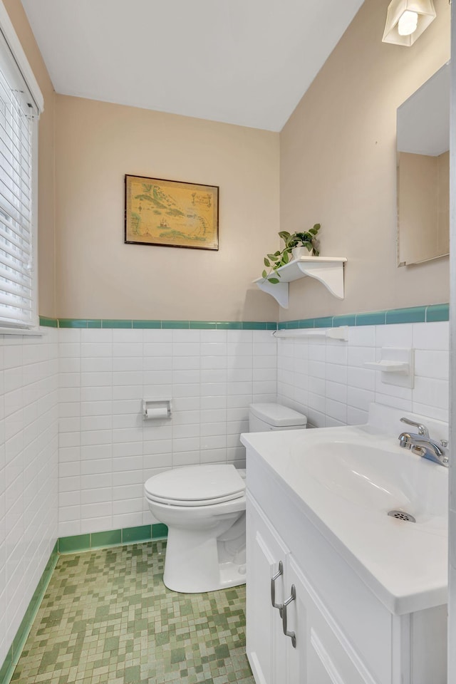 bathroom with tile walls, wainscoting, vanity, and toilet