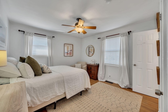 bedroom featuring baseboards, light wood-style flooring, visible vents, and a ceiling fan