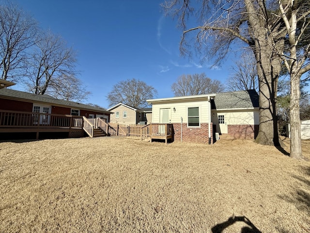 rear view of house featuring brick siding and a wooden deck