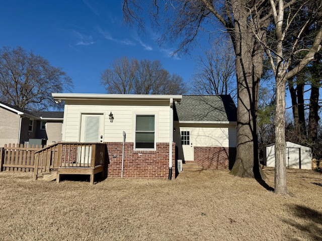 rear view of property with roof with shingles, fence, and brick siding