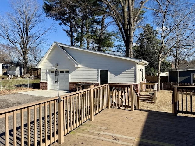 deck with concrete driveway, a detached garage, and fence