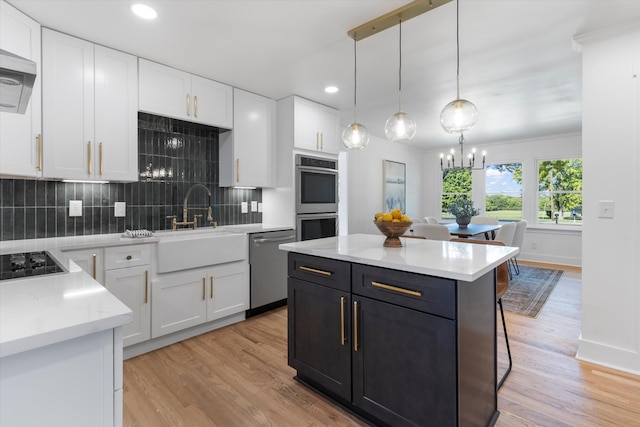 kitchen with decorative backsplash, appliances with stainless steel finishes, light wood-type flooring, decorative light fixtures, and white cabinets