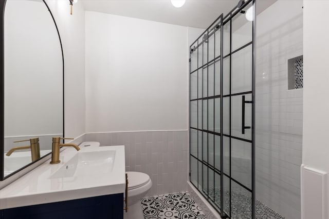 bathroom with vanity, tiled shower, tile walls, tile patterned flooring, and toilet