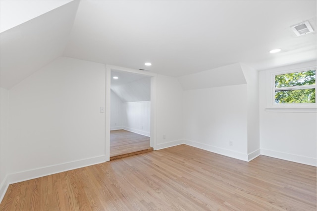 additional living space featuring light wood-type flooring and vaulted ceiling