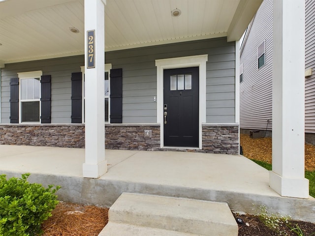 view of exterior entry featuring covered porch