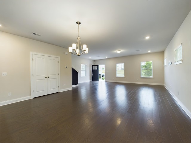 unfurnished living room featuring dark hardwood / wood-style flooring, a wealth of natural light, and a notable chandelier