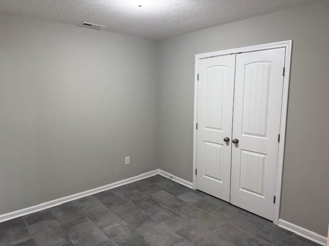 unfurnished bedroom featuring a textured ceiling and a closet