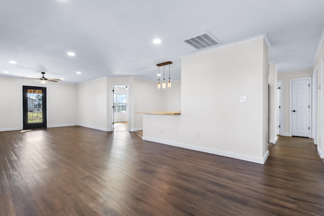 unfurnished living room featuring ceiling fan, a wealth of natural light, crown molding, and dark wood-type flooring