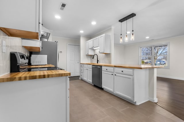 kitchen with decorative light fixtures, white cabinets, and wood counters