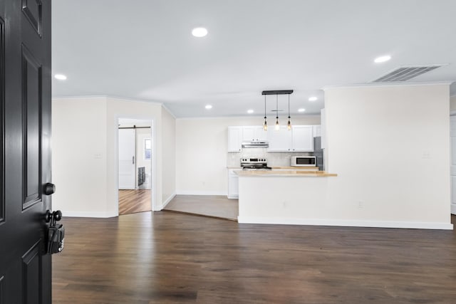 living room featuring dark hardwood / wood-style floors, crown molding, and a barn door