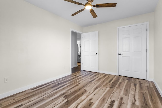 unfurnished bedroom with ceiling fan, stainless steel refrigerator, and wood-type flooring