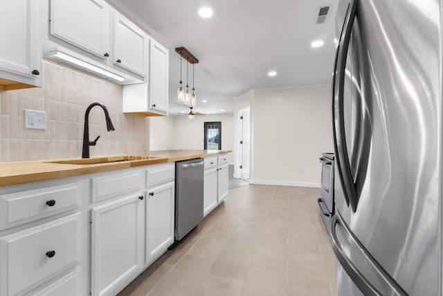 kitchen with wooden counters, decorative light fixtures, white cabinetry, stainless steel appliances, and sink