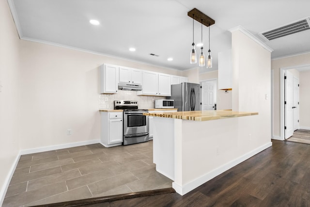 kitchen with appliances with stainless steel finishes, hanging light fixtures, decorative backsplash, white cabinets, and wood counters