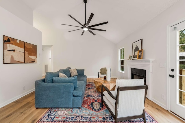 living room with ceiling fan, light hardwood / wood-style floors, and vaulted ceiling