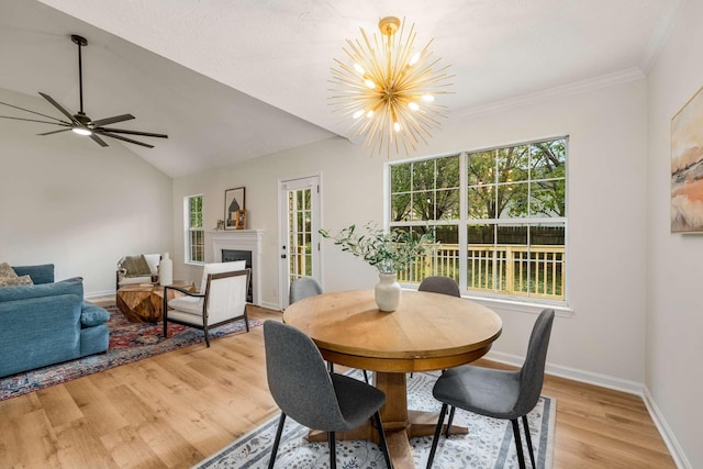 dining area featuring vaulted ceiling, crown molding, ceiling fan with notable chandelier, and light wood-type flooring