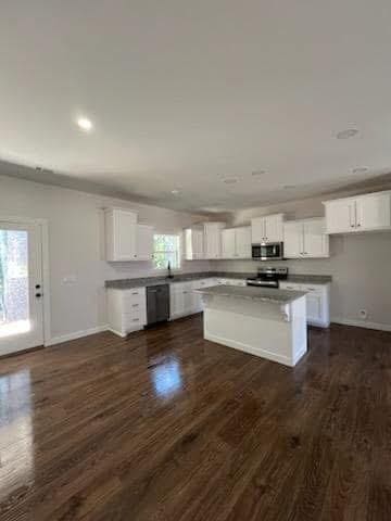 kitchen featuring white cabinetry, a kitchen island, dark wood-type flooring, and appliances with stainless steel finishes