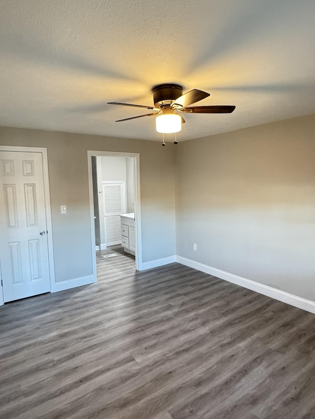 unfurnished bedroom with ensuite bathroom, dark hardwood / wood-style flooring, ceiling fan, and a textured ceiling