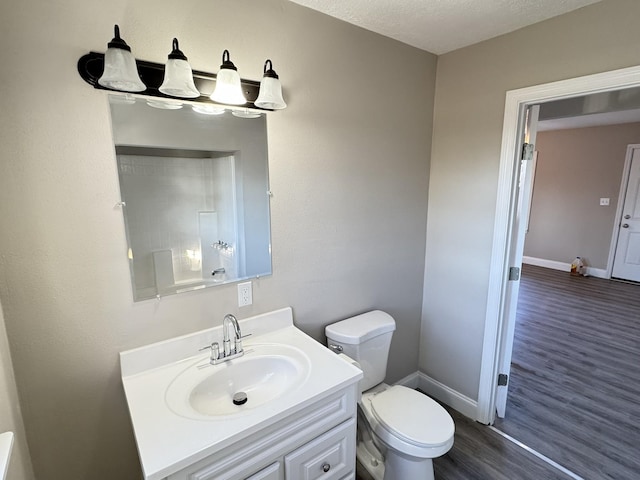 bathroom featuring vanity, wood-type flooring, a textured ceiling, and toilet