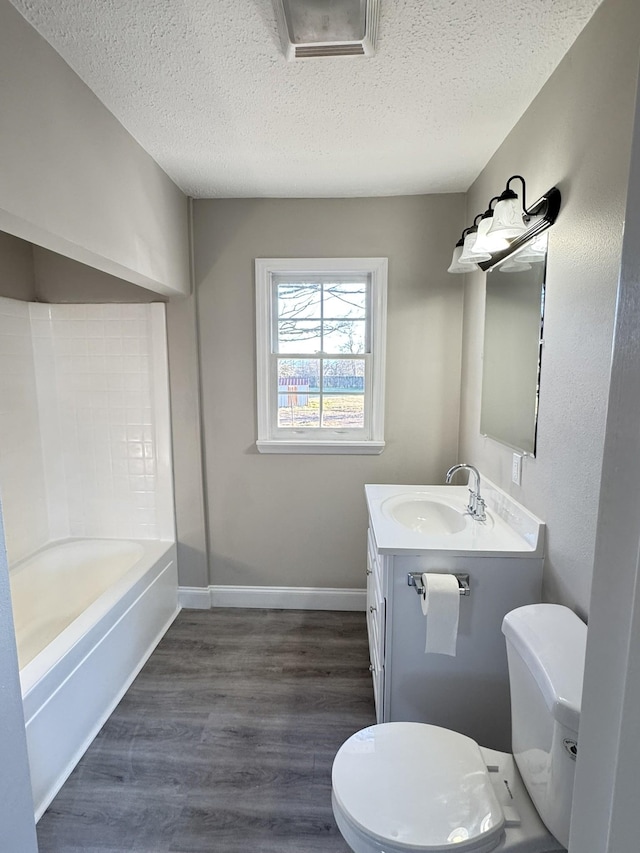 bathroom with hardwood / wood-style flooring, vanity, a textured ceiling, and toilet