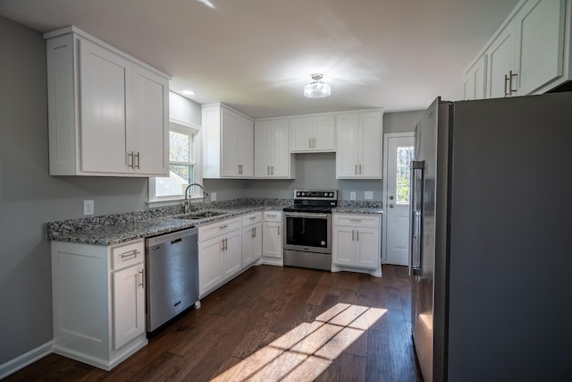 kitchen featuring white cabinetry, dark wood-type flooring, light stone counters, and appliances with stainless steel finishes