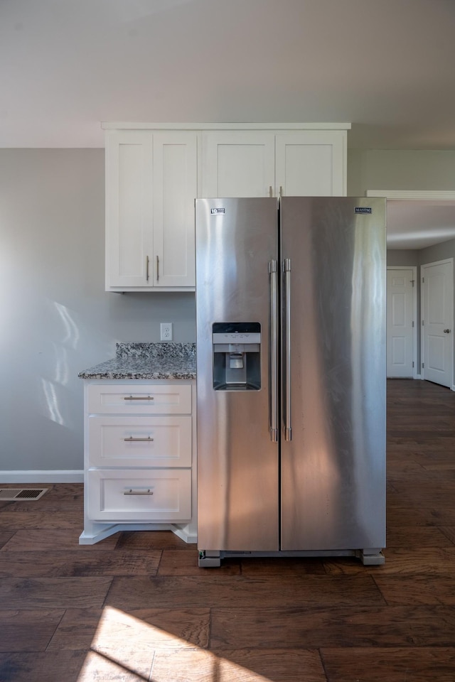 kitchen featuring white cabinets, stainless steel fridge, light stone counters, and dark wood-type flooring