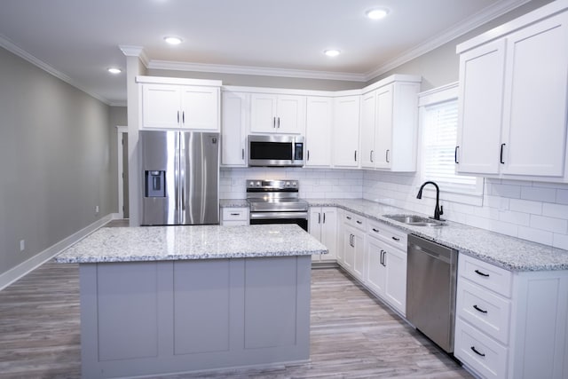 kitchen with white cabinets, appliances with stainless steel finishes, a kitchen island, and sink