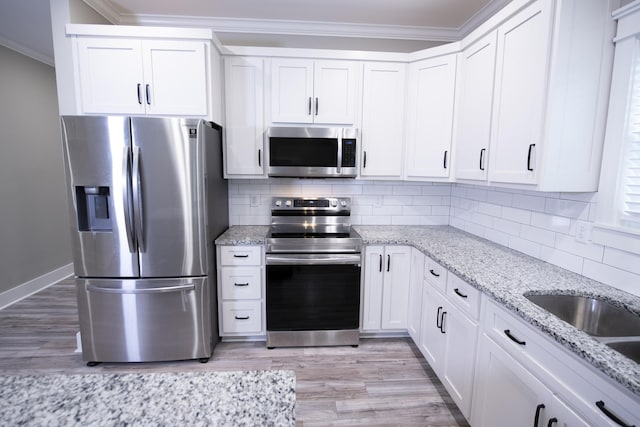 kitchen with decorative backsplash, light stone countertops, white cabinetry, and appliances with stainless steel finishes