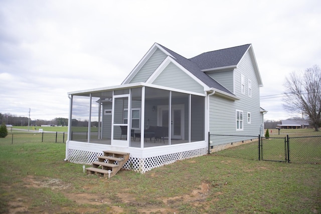 rear view of house featuring a sunroom and a lawn