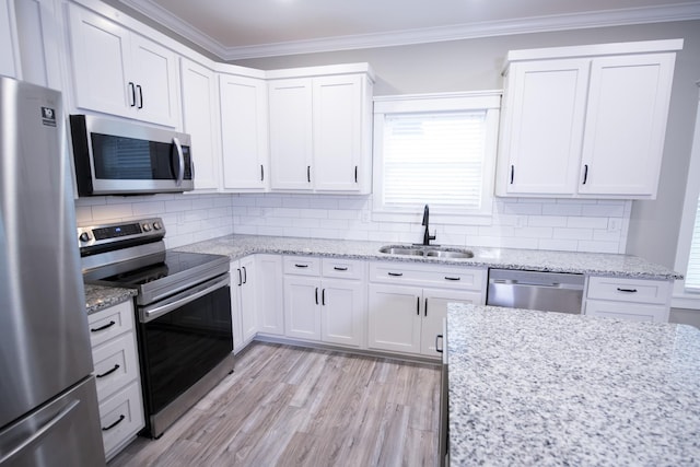 kitchen with backsplash, sink, light stone counters, white cabinetry, and stainless steel appliances