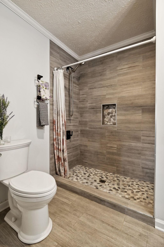 bathroom featuring a shower with shower curtain, a textured ceiling, toilet, and crown molding