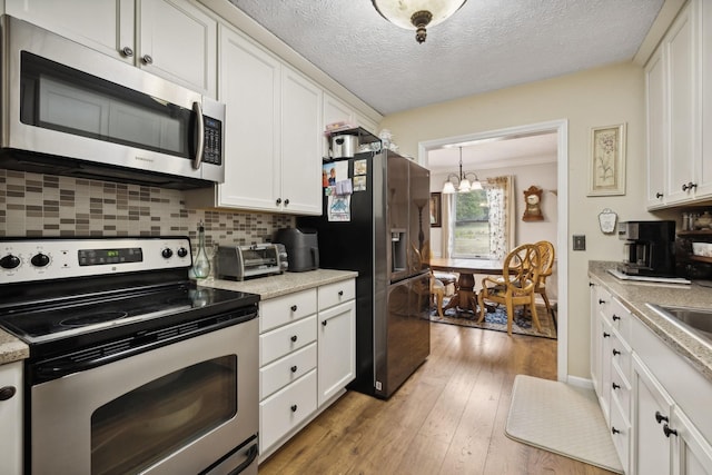 kitchen featuring a chandelier, white cabinetry, appliances with stainless steel finishes, and tasteful backsplash