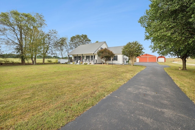 view of front of property with an outbuilding, covered porch, a front yard, and a garage