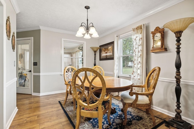 dining room with hardwood / wood-style floors, a textured ceiling, crown molding, and a chandelier