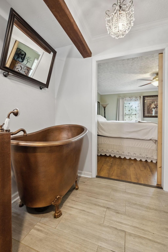 bathroom featuring a textured ceiling, ceiling fan, crown molding, beamed ceiling, and a bathing tub