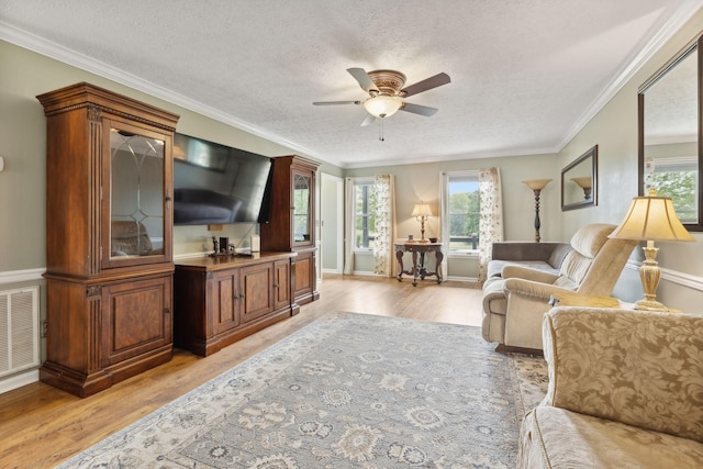 living room featuring a textured ceiling, light hardwood / wood-style floors, ceiling fan, and ornamental molding