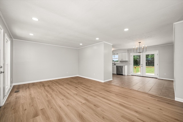 unfurnished living room with french doors, ornamental molding, and light wood-type flooring