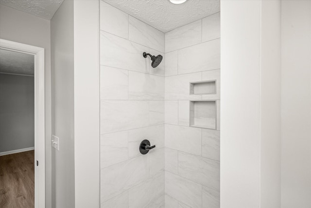 bathroom featuring hardwood / wood-style flooring, a textured ceiling, and tiled shower