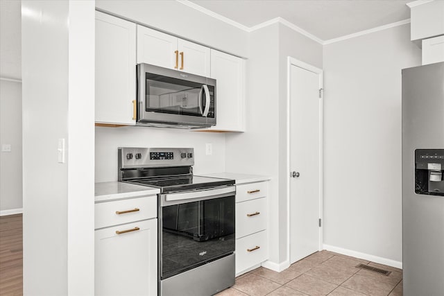 kitchen with white cabinets, light tile patterned flooring, ornamental molding, and stainless steel appliances